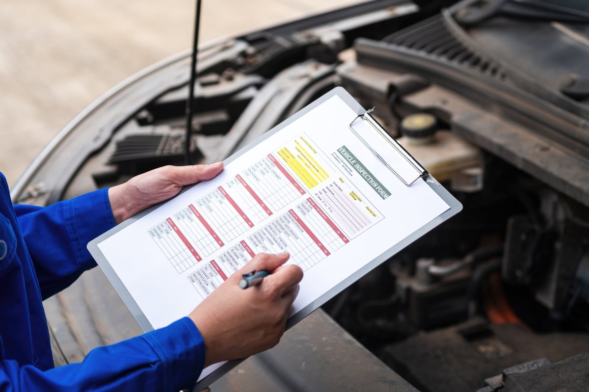 Car service technician checking a vehicle inspection checklist