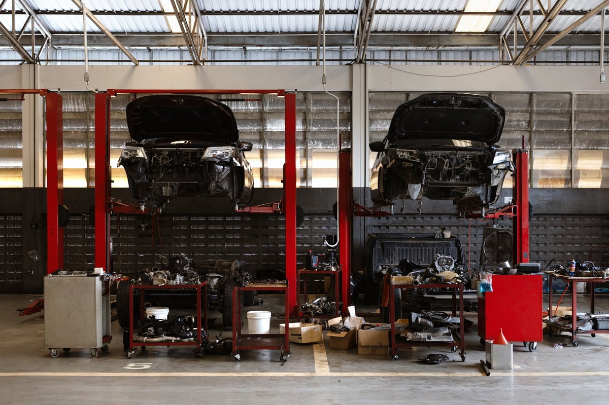 Auto repair workshop with vehicles on hydraulic lifts during engine maintenance